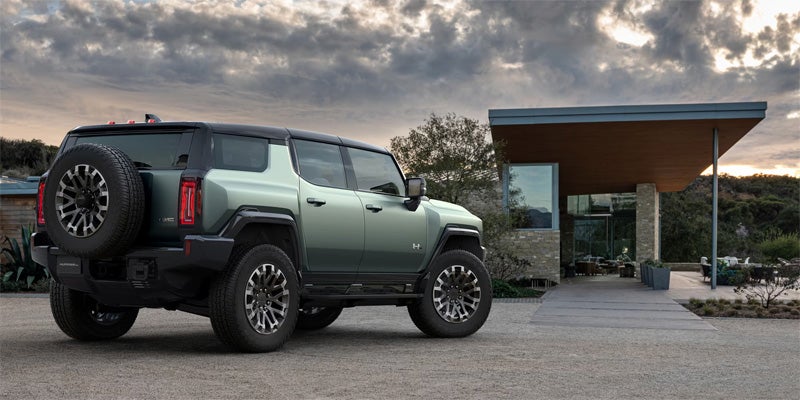Green GMC Hummer EV SUV standing near charging station