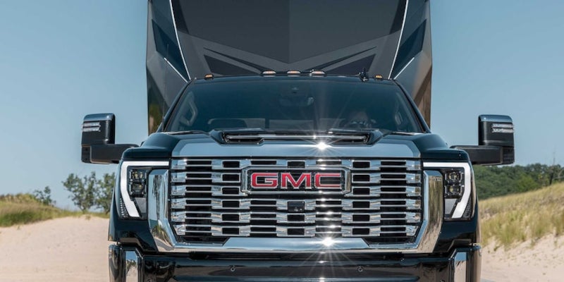 Black gmc sierra running on road towing at back