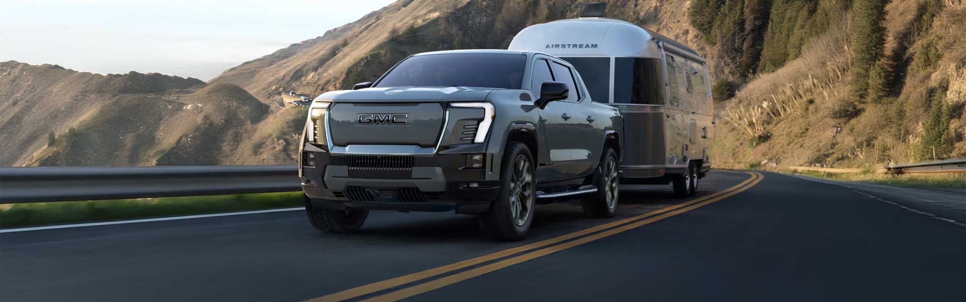 2024 GMC Sierra EV running on road with towing at back