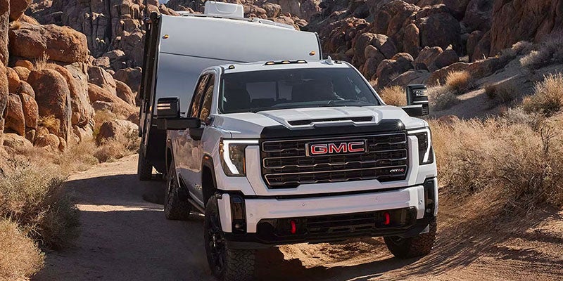white gmc sierra running on road towing at back