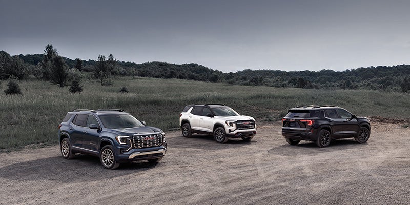Three SUVs parked side by side on a dirt road surrounded by greenery.