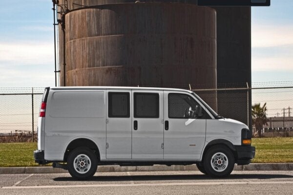 white GMC Savana Van standing outside on road